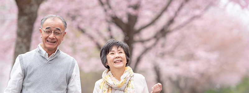 桜並木を笑顔で歩く男女（イメージ画像）